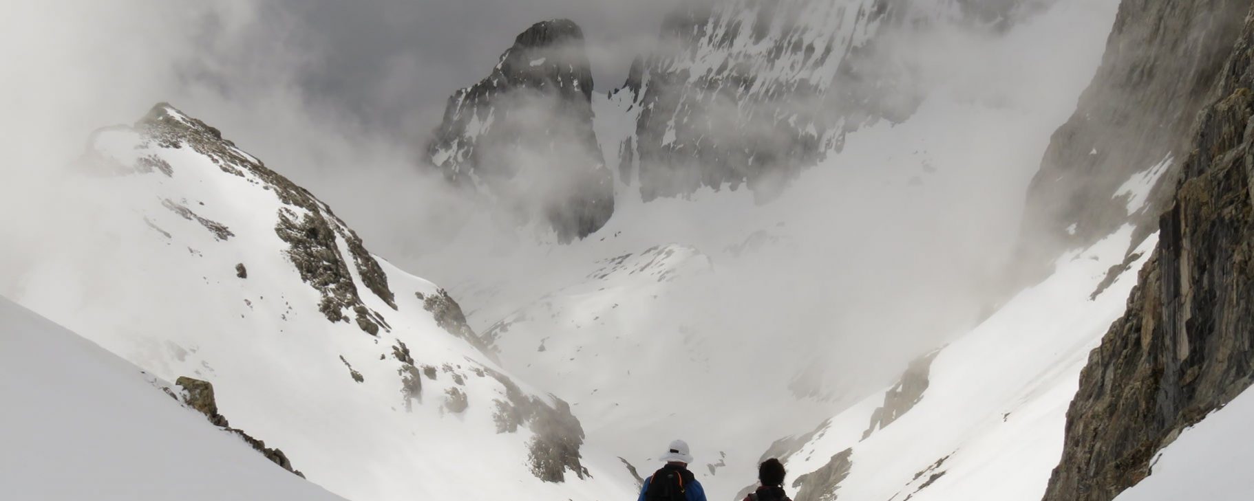 Lea y Xita bajando por la Canal Fonda, enfrente las Crestas del Forcau entre nubes