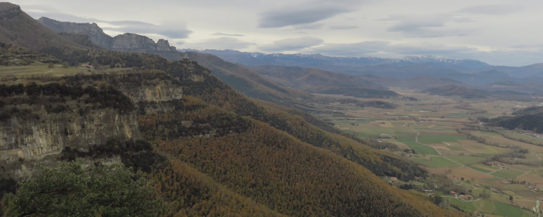 A la izquierda Sant Miquel de Castelló, Pibernat, detrás el Puig Cornell, Puigsacalm, a la derecha el valle de la Vall d’en Bas y al fondo el Pirineo