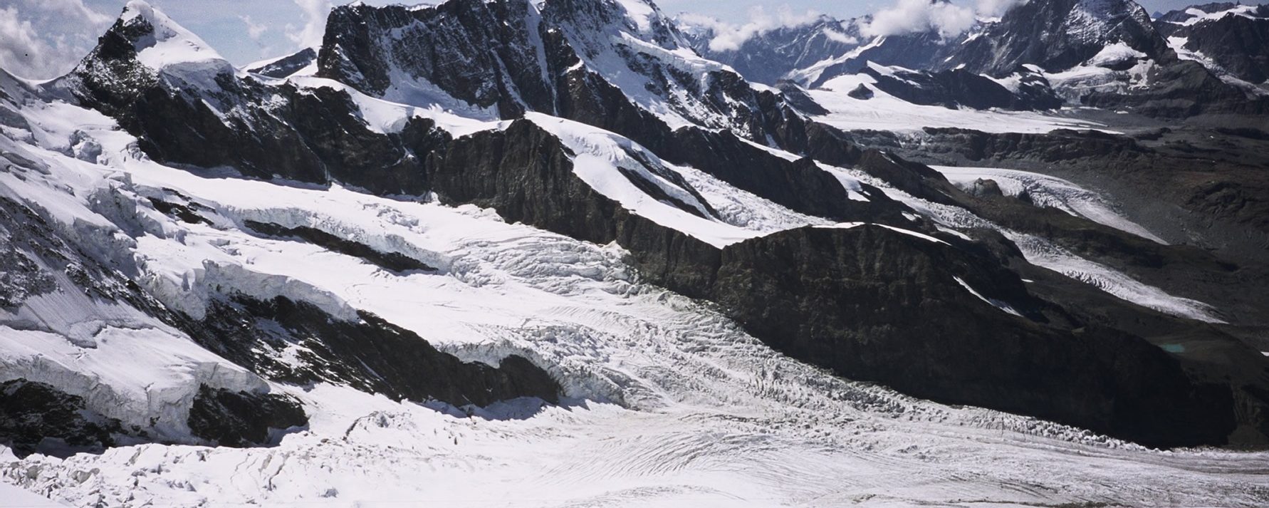 Joaquín Terrés bajando por el Glaciar del Monte Rosa, delante el Breithorn con el Pollux a la izquierda, el Glaciar Grenx abajo, con el Dent d’Hèrens y Cervino a la derecha entre nubes