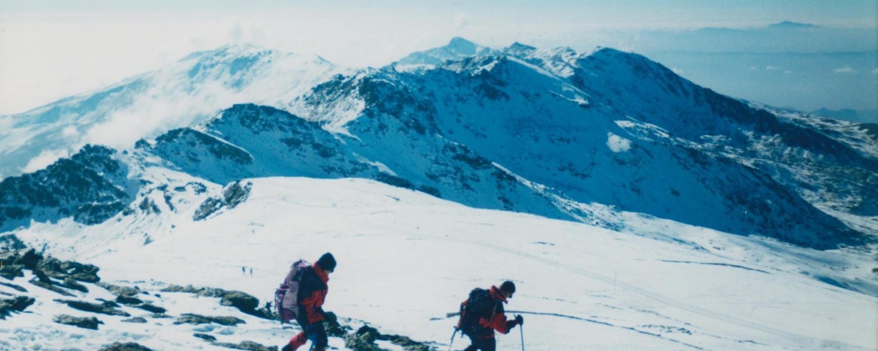Antonio y Jesús bajando a La Carihuela, dicho collado a la izquierda, el centro a la izquierda los Tajos de La Virgen y Pico del Tajo de Los Machos detrás entre nubes, en el centro Elorrieta y Caballo detrás, a la derecha Cartujo y al fondo la Sierra de Tejeda